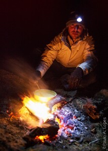 Aquecer comida na fogueira à noite na montanha
